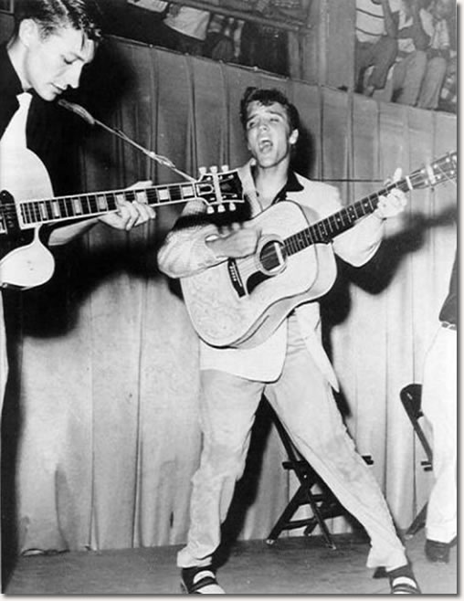 A young Elvis Presley performs at the Fort Homer W. Hesterly Armory, Tampa, FL July 31, 1955. Scotty Moore is on the left.
